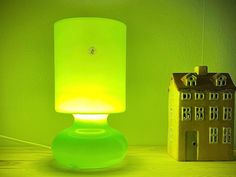 a green lamp sitting on top of a wooden table next to a toy house and dollhouse