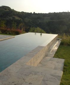 an empty swimming pool surrounded by lush green hills