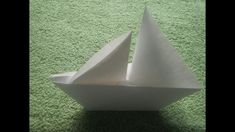 a white paper boat sitting on top of a green carpet