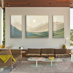 a living room with three paintings on the wall and two couches in front of them