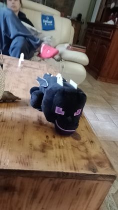 two stuffed animals sitting on top of a wooden table next to a woman in a chair