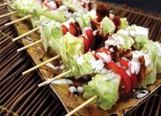 several lettuce and tomato skewers with dressing on them