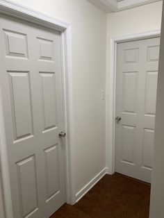 an empty room with two white doors and hard wood flooring on the other side