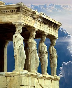 some statues are standing on the side of a building with clouds in the sky behind them