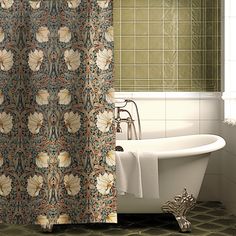 a bath tub sitting next to a shower curtain in a bathroom with green tiles on the walls