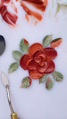 a white plate topped with red flowers and two spoons