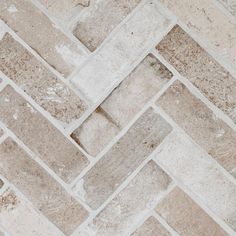 a close up view of a brick floor with white and brown tiles on the side