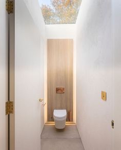 a white bathroom with a skylight above the toilet and door to the other room