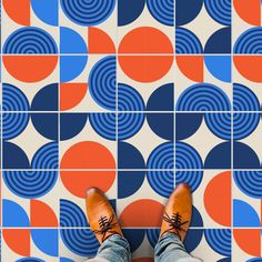 a person standing in front of a tiled floor with orange and blue circles on it