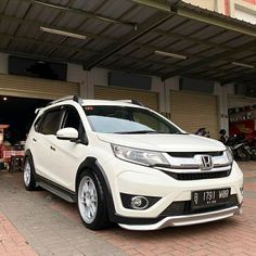 a white honda cr - v parked in front of a garage