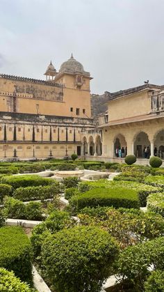 the courtyard of an old palace with hedges and bushes