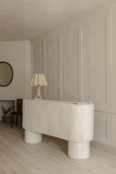 a large white table sitting in the middle of a living room next to a lamp