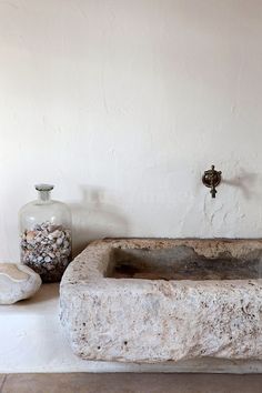 a stone bathtub sitting next to a glass bottle