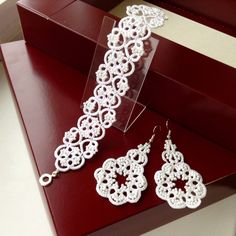 a pair of white crochet earrings on display in a red box with the lid open