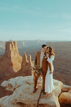 a man and woman standing on top of a cliff