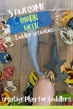 a child's hand is playing with toys in the shape of sharks and octopuses