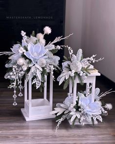 two white vases filled with flowers on top of a wooden table next to each other