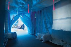 an image of a bed room with blue curtains on the walls and lights hanging from the ceiling