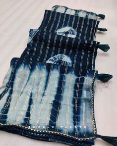 three pieces of blue and white tie - dyed fabric with tassels on them