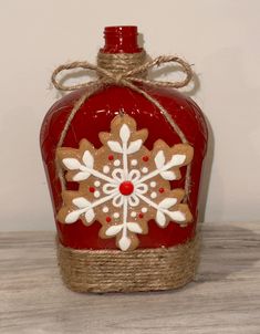 a red bottle with a snowflake design on it and rope wrapped around the top