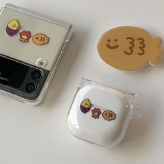 two cell phones sitting next to each other on top of a white table with stickers