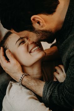 a man kissing a woman's face while she is holding her head close to her chest