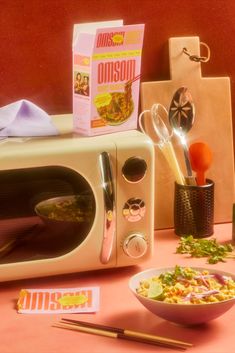 a microwave oven sitting on top of a table next to a bowl of food and chopsticks