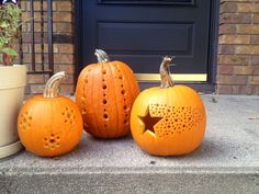 three carved pumpkins sitting on the front steps