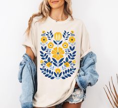 Are you looking for the perfect Scandinavian Folk Art Unisex T-shirt, Folk Art Tshirt, Cottagecore Shirt, Botanical Shirt, Boho Wildflowers Shirt, Scandi Folk Art Shirt? Look no further! Colors: Image 1: Ivory Image 2: Ivory Image 3: Light Green Image 4: Light Green Image 5: White Image 6: Yam Image 7: Crunchberry Image 8: Berry Image 9: Watermelon Comfort Colors introduces the "Comfort Colors 1717" garment-dyed t-shirt; a fully customizable tee made 100% with ring-spun cotton. The soft-washed, Spring Folk Style Embroidered Shirt, Spring Bohemian T-shirt With Screen Print, White Folk Shirt With Floral Embroidery, Cottagecore Cotton Printed T-shirt, Spring Bohemian T-shirt With Graphic Print, T Shirt Art, Cottagecore Shirt, Botanical Shirt, Scandinavian Folk Art