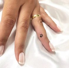 a woman's hand with a small dog paw tattoo on her left ring finger