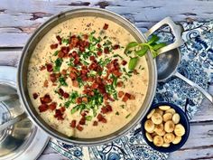 a bowl of soup with bacon and green garnish next to some silverware