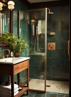 a bathroom with green tile and gold fixtures on the shower door, sink, and mirror