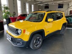 a yellow jeep is parked in a showroom