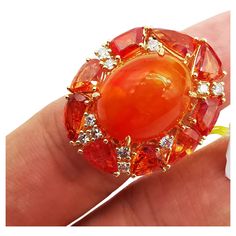 The Following Item we are offering is a Rare Important Radiant 18KT Gold Large Fancy Fiery Orange Opal Diamond Orange Sapphire Ring. Ring is comprised of A LARGE Gorgeous Fancy Fiery Orange Opal surrounded by a Beautiful Halo of Fancy Orange Sapphires and Diamonds!! T.C.W APPROX 14.50CTS!!! Comes with New with Tags from a Private Manufacturer that sells to Important 5 Star Hotel and Fine Jewelry Stores. Original Retail Price: $9,209.00!!! A Gorgeous Masterpiece!!! Luxury Gold Gemstones For Wedding, Luxury High Luster Gemstones For Formal Occasions, Luxury Cluster Ruby Ring Gift, Luxury Yellow Gold Cluster Ring With Accent Stones, Luxury Cluster Ring In Yellow Gold With Accent Stones, Elegant Multi-stone Orange Rings, Yellow Gold Multi-stone Rings For Party, Luxury Cluster Ring Gift, Orange Multi-stone Jewelry For Formal Occasions