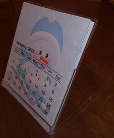 a calendar with a snowman on the front and numbers in the back, sitting on top of a wooden table