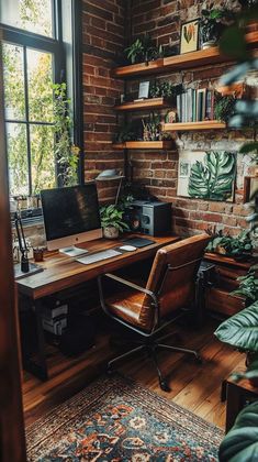 a home office with brick walls and lots of greenery on the desk, along with a large window