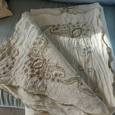 two white bedspreads sitting on top of a bed next to pillows and blankets