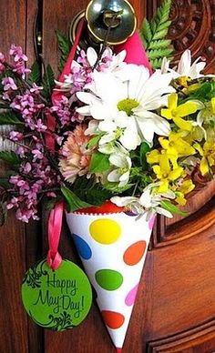 a bouquet of flowers in a polka dot cone hanging on a doorknob with a happy mother's day tag