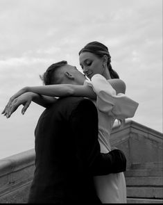 a man and woman embracing each other in front of a building