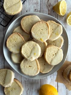 lemon shortbreads with icing on a white plate next to sliced lemons