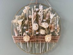 an arrangement of dried flowers is hanging on the wall