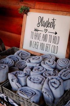 a basket filled with blue towels next to a sign that reads blankets to have and to hold in case you get cold