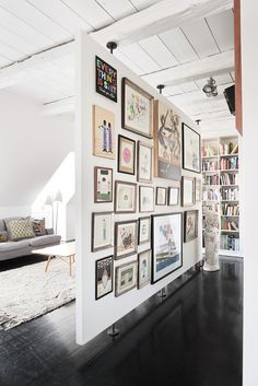 a living room filled with lots of framed pictures on the wall next to a couch