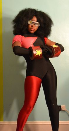 a woman in a black and red outfit with stars on her chest, holding a pair of gloves