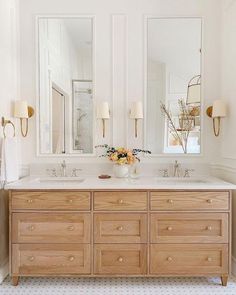 a bathroom with two sinks and three mirrors on the wall above it is decorated with flowers