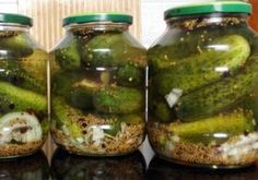 three jars filled with pickles sitting on top of a counter