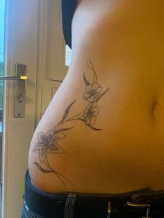 a woman's stomach with a flower tattoo on her side and the bottom part of her belly