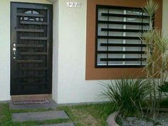 a black door is in front of a white house with brown shutters and grass