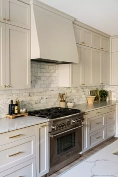 a kitchen with marble counter tops and white cabinets, along with a stainless steel stove top oven