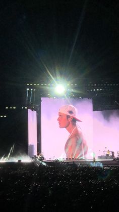 a man standing on top of a stage under a large screen